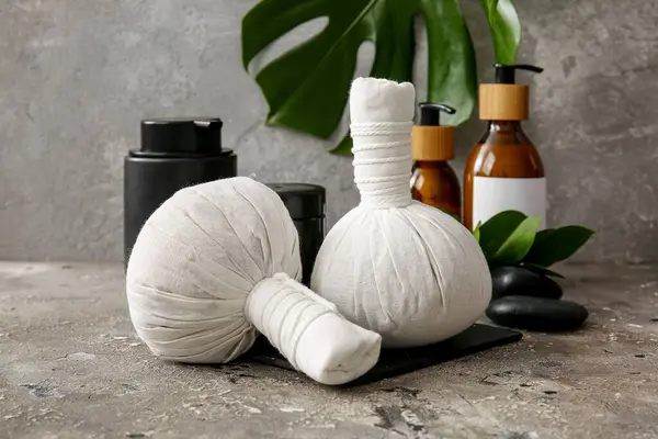 Herbal massage bags and cosmetic products on grunge background