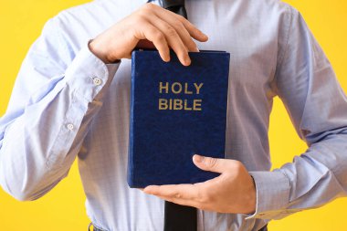 Sarı arka planda İncil 'i olan genç adam, yakın plan.