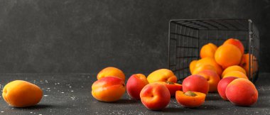 Ters dönmüş sepet ve siyah arka planda dağınık kayısılar.  