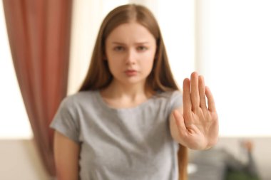 Çürümüş genç bir kadın evde dur işareti yapıyor, yakın plan. Aile içi şiddet kavramı