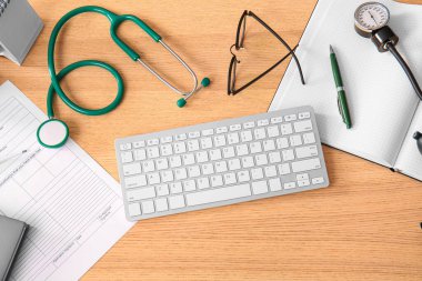 Tahta masanın üstünde tıbbi malzemeler olan bilgisayar klavyesi.