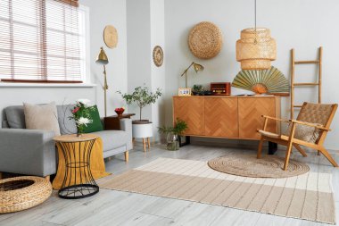 Oturma odasının içinde kanepe, çekmece ve ikebana var.