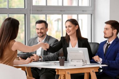 İnsan kaynakları müdürü, kadın başvuru sahibinin elini sıkıyor.