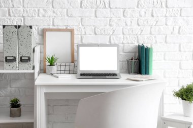 Boş dizüstü bilgisayarı ve yapay tesisi olan modern işyeri