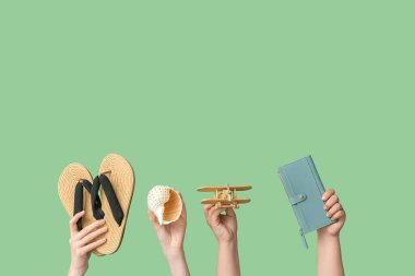 Parmak arası terlikli kadın eller, yeşil arka planda tahta uçak ve cüzdan. Seyahat kavramı