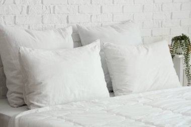 Yatak odasının içinde beyaz battaniyeli ve yastıklı rahat bir yatak.