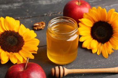 Rosh Hashanah kutlaması için elmalı ve ayçiçekli bal kavanozu (Yahudi Yeni Yılı) siyah ahşap masada