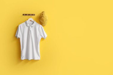 Sarı arka planda asılı şık beyaz tişört ve şapka