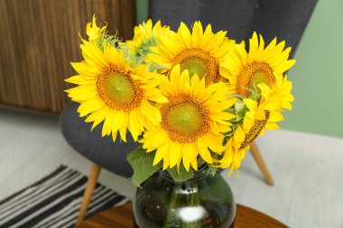 Vase with sunflowers on table in living room, closeup