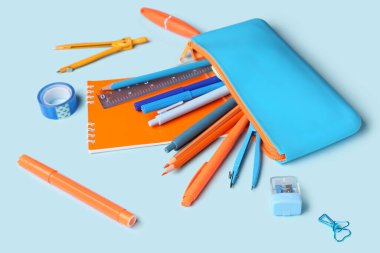 Mavi arka planda farklı okul kırtasiyesine sahip şık kalem kutusu, yakın plan.