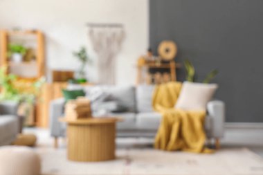 Gri kanepe ve ahşap sehpa ile aydınlık oturma odasının bulanık görüntüsü
