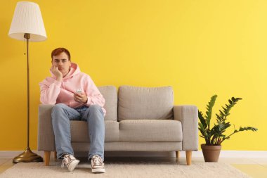 Klimalı, uzaktan kumandalı sinirli genç adam evde oturuyor.