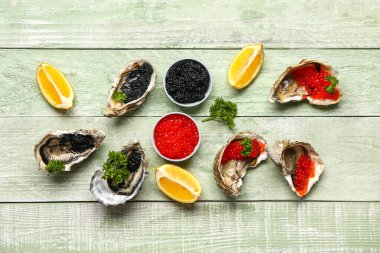 Limonlu lezzetli istiridye, yeşil ahşap arka planda siyah ve kırmızı havyar.