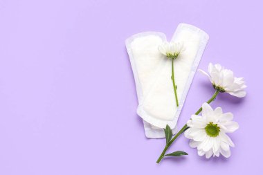 Leylak arka planında regl pedleri ve papatya çiçekleri