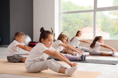 Beden dersinde yoga yapan bir grup çocuk.