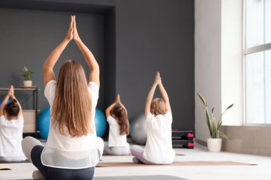 Beden eğitimi dersinde bir grup küçük çocukla yoga eğitmeni.