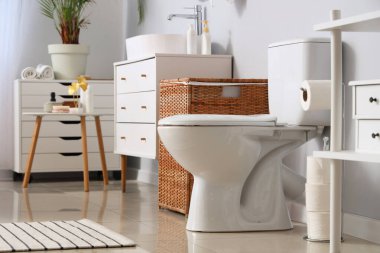 Tuvalet klozeti ve hasır sepeti olan ışık tuvaletinin içinde.