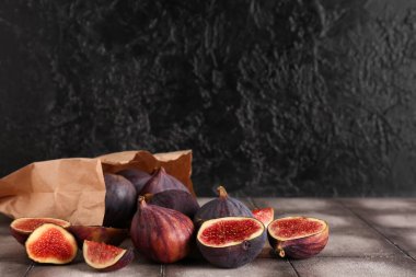 Gri fayansların üzerinde taze incir dolu kağıt torba.