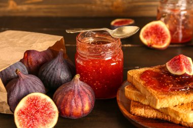 Kavanoz dolusu tatlı incir reçeli ve ahşap arka planda lezzetli tost tabağı.