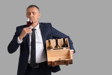 Cam ve şarap şişeleriyle donatılmış olgun bir adam.