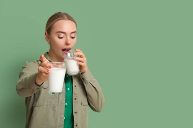 Yeşil arka planda süt bardakları olan güzel genç bir kadın.