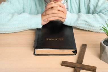 İncil 'i olan genç ve güzel bir Asyalı kadın oturma odasında dua ediyor.