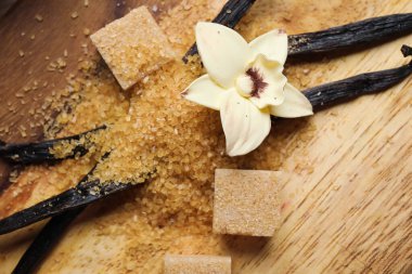 Aromatik vanilya şekeri, çiçek ve tahta zemin üzerinde çubuklar