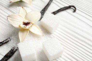 Aromatik vanilya şekeri, çiçek ve sopalar beyaz ahşap arka planda