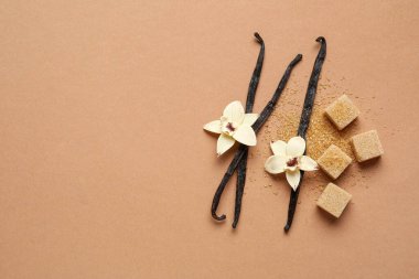 Aromatik vanilya şekeri, çiçekler ve kahverengi arka planda çubuklar