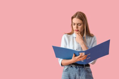 Pembe arka planda doküman klasörüne sahip düşünceli genç iş kadını.