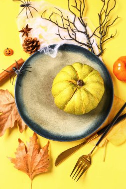 Sarı arka planda balkabakları ve yaprakları olan Cadılar Bayramı masası