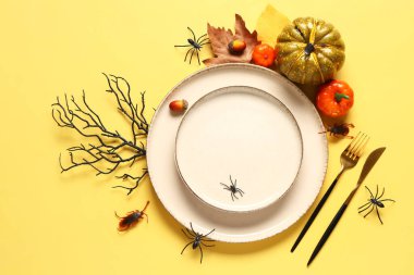 Sarı arka planda balkabakları, örümcekler ve sonbahar yapraklarıyla Cadılar Bayramı sofrası