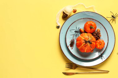 Sarı arka planda balkabakları ve örümceklerle Cadılar Bayramı sofrası