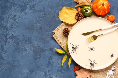 Mavi grunge arka planda balkabakları, örümcekler ve sonbahar yapraklarıyla Cadılar Bayramı sofrası