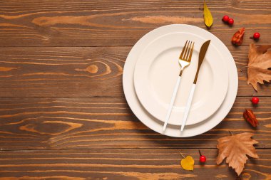 Ahşap zemin üzerinde boş tabak ve çatal bıçak takımı ile sonbahar masası ayarları