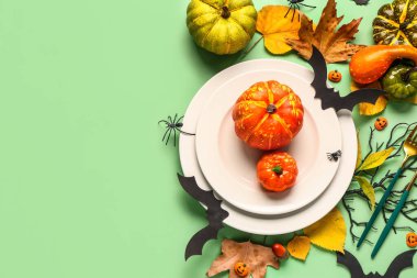 Yeşil arka planda balkabakları, yaprakları ve dekoru olan Cadılar Bayramı sofrası