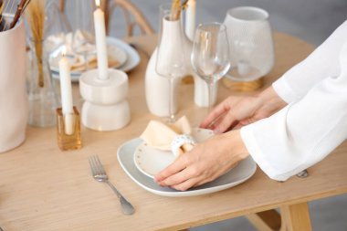 Kadın elleri yemek odasında masayı hazırlıyor, yakın plan.