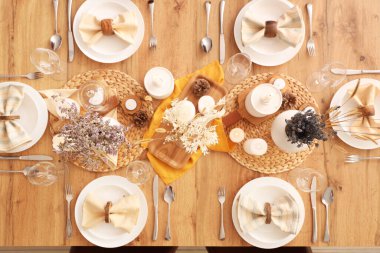 Kurumuş çiçekleri, yanan mumları ve kozalakları olan zarif bir masa.