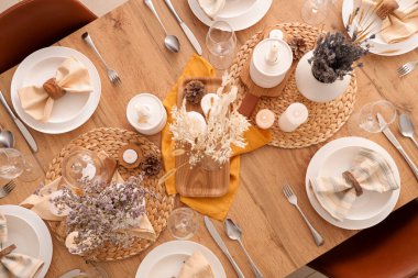 Kurumuş çiçekleri, yanan mumları ve kozalakları olan zarif bir masa.