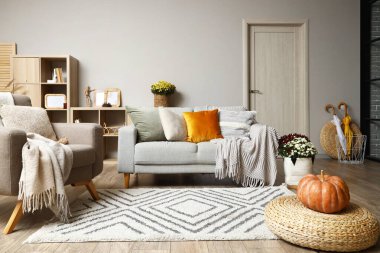 Gri kanepesi, koltuğu ve kabağı hasır pouf üzerinde olan şık bir oturma odası.