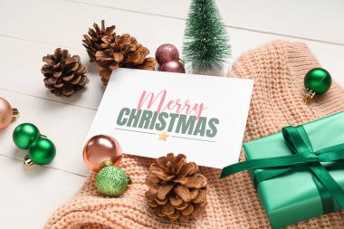 Tebrik kartı, hediye kutusu ve beyaz ahşap arka planda dekoru olan güzel bir Noel kompozisyonu.