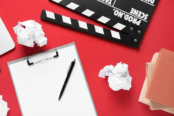 Clipboard with crumpled paper, books and movie clapper on red background