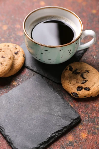 Drink coasters with cup of coffee, cookies and cinnamon on brown grunge table