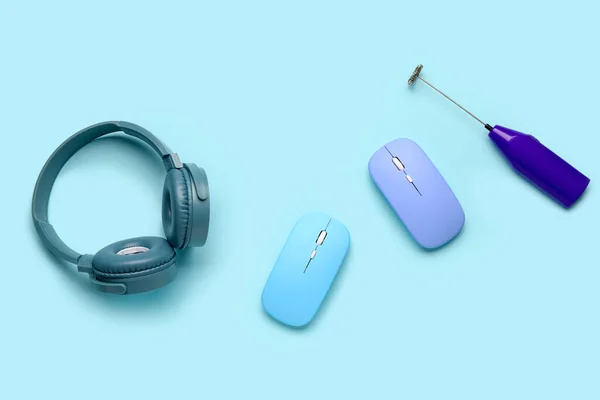 Modern headphones with computer mouses and mixer on blue background