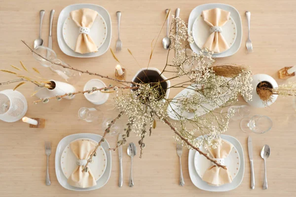 Elegant table setting with candles, dried flowers in vases and glasses