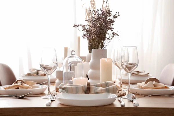 Elegant table setting with dried flowers, burning candles and glasses