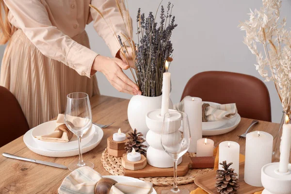 Woman decorating table with dried flowers in dining room