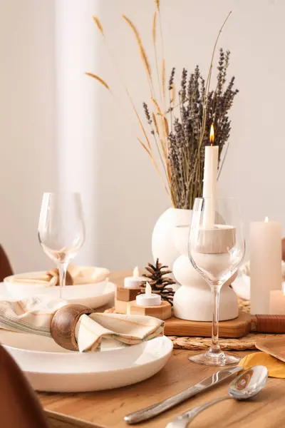 Elegant table setting with dried flowers, burning candles and pine cones