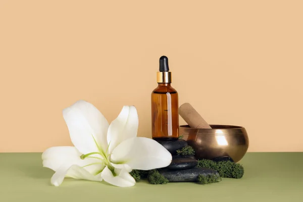 Composition with bottle of essential oil, spa accessories and lily flower on color background