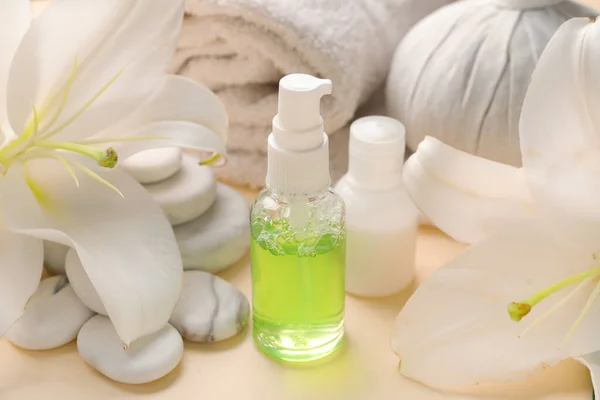 Bottles of cosmetic products, spa accessories and lily flowers on color background, closeup